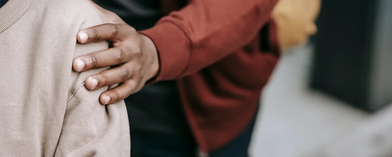 A hand resting supportively on someone's shoulder